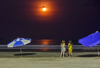 Men with umbrella against sky at night