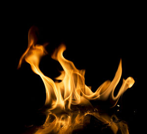 Close-up of burning candle against black background