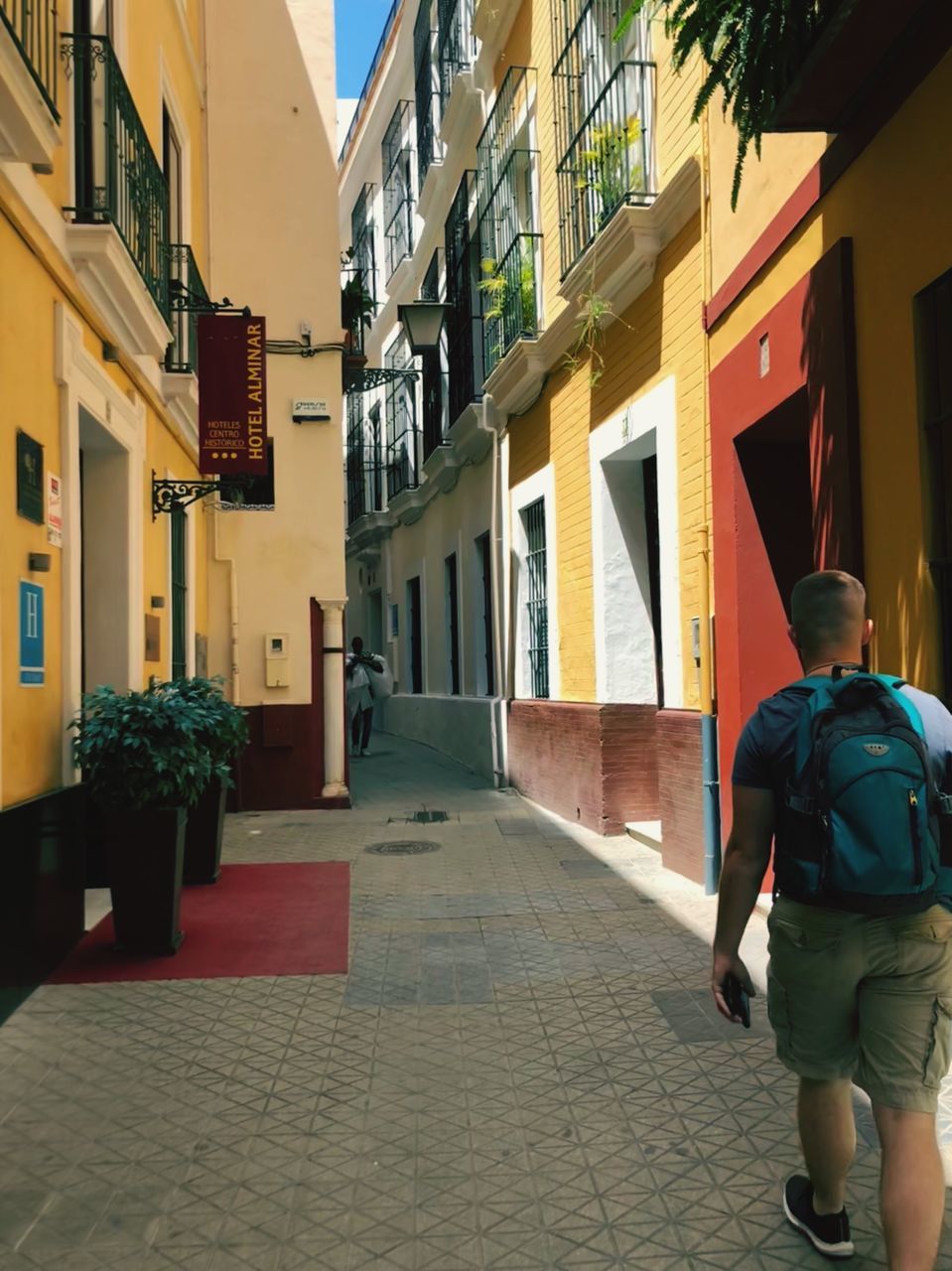 built structure, architecture, building exterior, real people, rear view, walking, one person, building, city, footpath, the way forward, street, lifestyles, direction, residential district, full length, window, adult, day, outdoors, alley