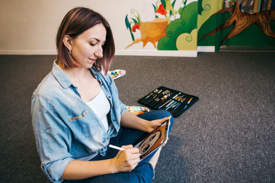 Young woman looking away while sitting on floor