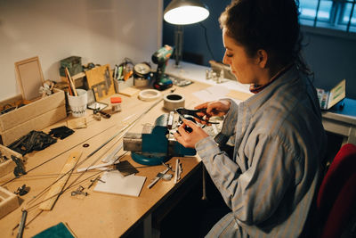 High angle view of female engineer working on equipment at desk in workshop