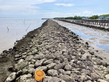 Surface level of stones on shore against sky