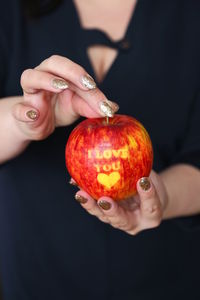 Midsection of woman holding apple with i love you text 