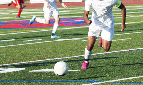 Low section of people playing soccer on grass
