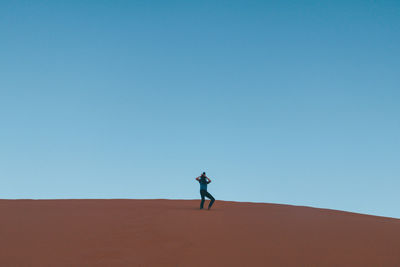 Man on sand dune against clear sky