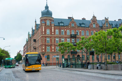 Cars on street by buildings in city against sky