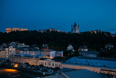 Illuminated buildings against blue sky at dusk