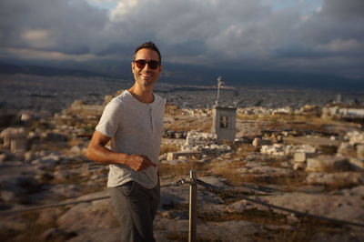 Portrait of smiling man standing by cityscape against sky