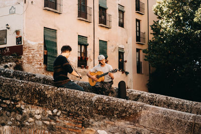 People playing guitar against building