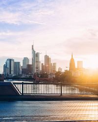 Modern skyscrapers against sky during sunset seen from bridge over main river