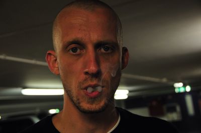 Close-up portrait of mid adult man smoking in subway