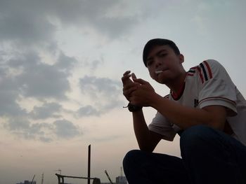 Low angle view of man sitting against sky