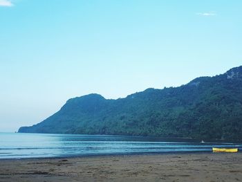 Scenic view of sea and mountains against clear blue sky