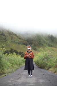 Full length of woman standing on road against sky