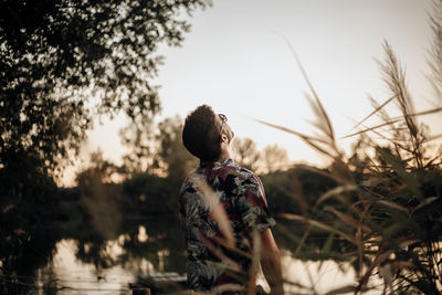 1. young man with sunglasses lookin the sky on his back at sunset