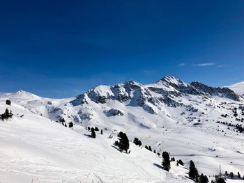 Scenic view of snow covered mountains against blue sky