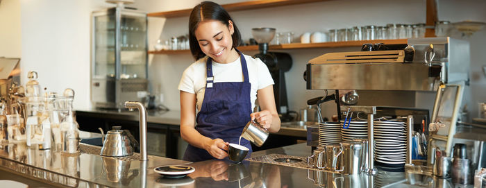 Side view of young woman using mobile phone in cafe