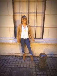 Portrait of young woman standing against wall