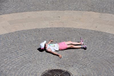 High angle view of girl lying on cobbled street