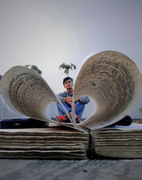 Full length of man sitting seen through book outdoors