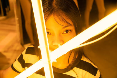 Close-up portrait of girl holding illuminated lighting equipment