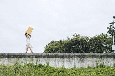 Rear view of man standing by trees against sky