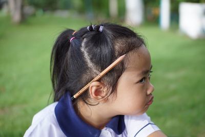 Close-up of cute girl with pencil on ear at park