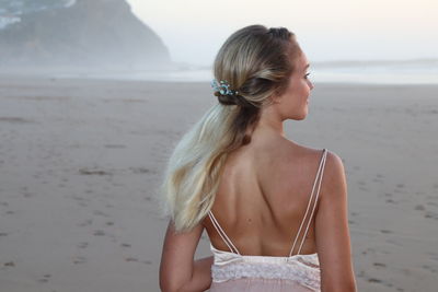 Midsection of woman standing at beach against sky