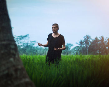 Young man standing on field against sky