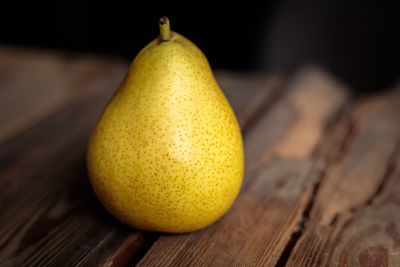 Juicy yellow pear on a wooden background from old boards in a low key.