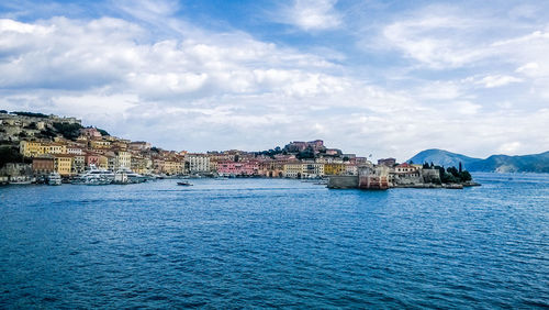 Buildings by sea against sky in city