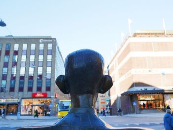 Rear view of statue against buildings in city