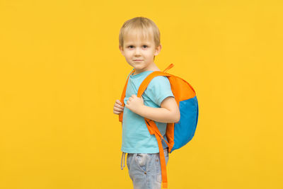 Portrait of boy standing against yellow background