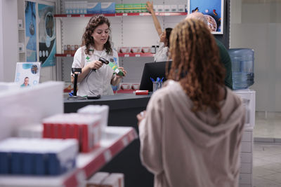 Rear view of woman using mobile phone while standing in store