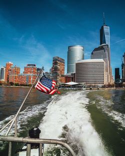 American flag on boat in river against skyscrapers