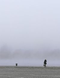 Man walking on riverbank against sky