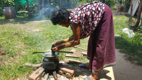 Side view of woman preparing food in yard