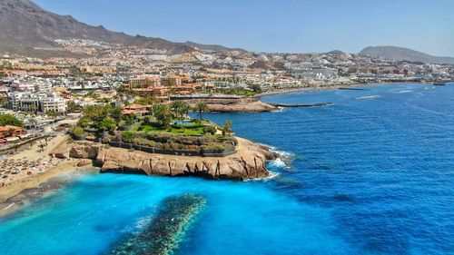 Aerial view of sea and buildings against clear blue sky