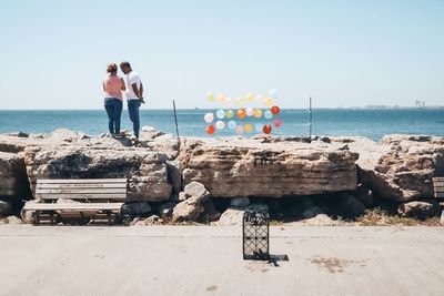 People standing at beach against sky