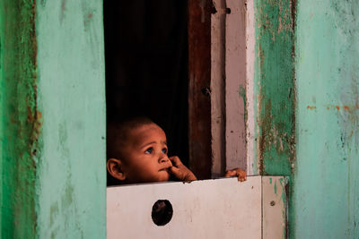 Portrait of cute boy peeking through window