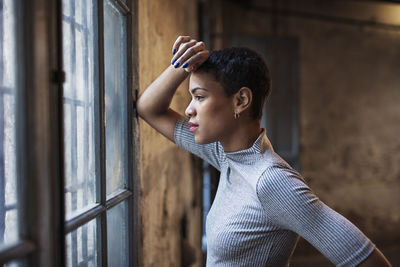 Side view of thoughtful businesswoman looking through window at workshop