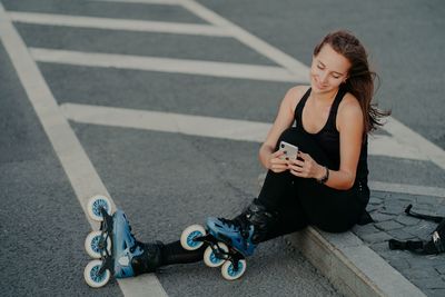 High angle view of young woman sitting on road