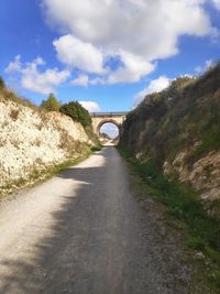 Road amidst arch bridge against sky