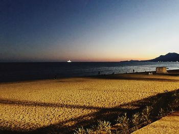 Scenic view of beach against clear sky during sunset