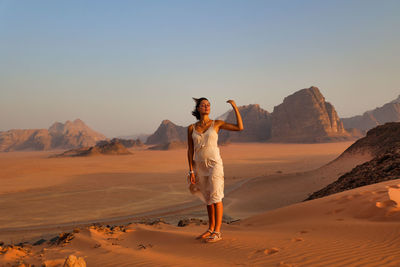 Full length of woman standing on sand at desert