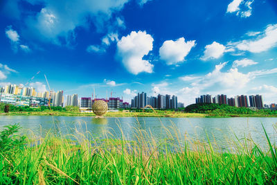 Scenic view of river by buildings against sky