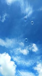 Low angle view of bubbles against blue sky