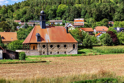 Old building by trees on field