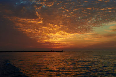 Scenic view of sea against dramatic sky during sunset