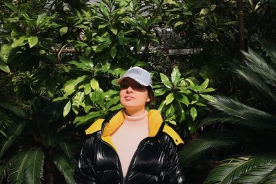 Portrait of young woman standing against plants